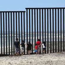 People Peering through Border Fence